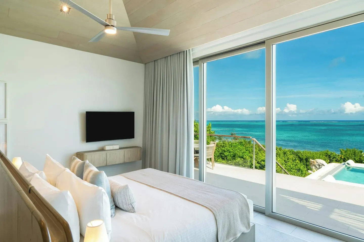 Ocean-view villa bedroom with king bed, glass doors, terrace, and sea view at Rock House.