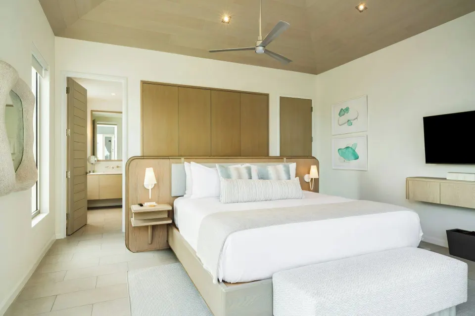 Ocean-view villa king bedroom with wardrobes, vanity doorway, and TV at Rock House.