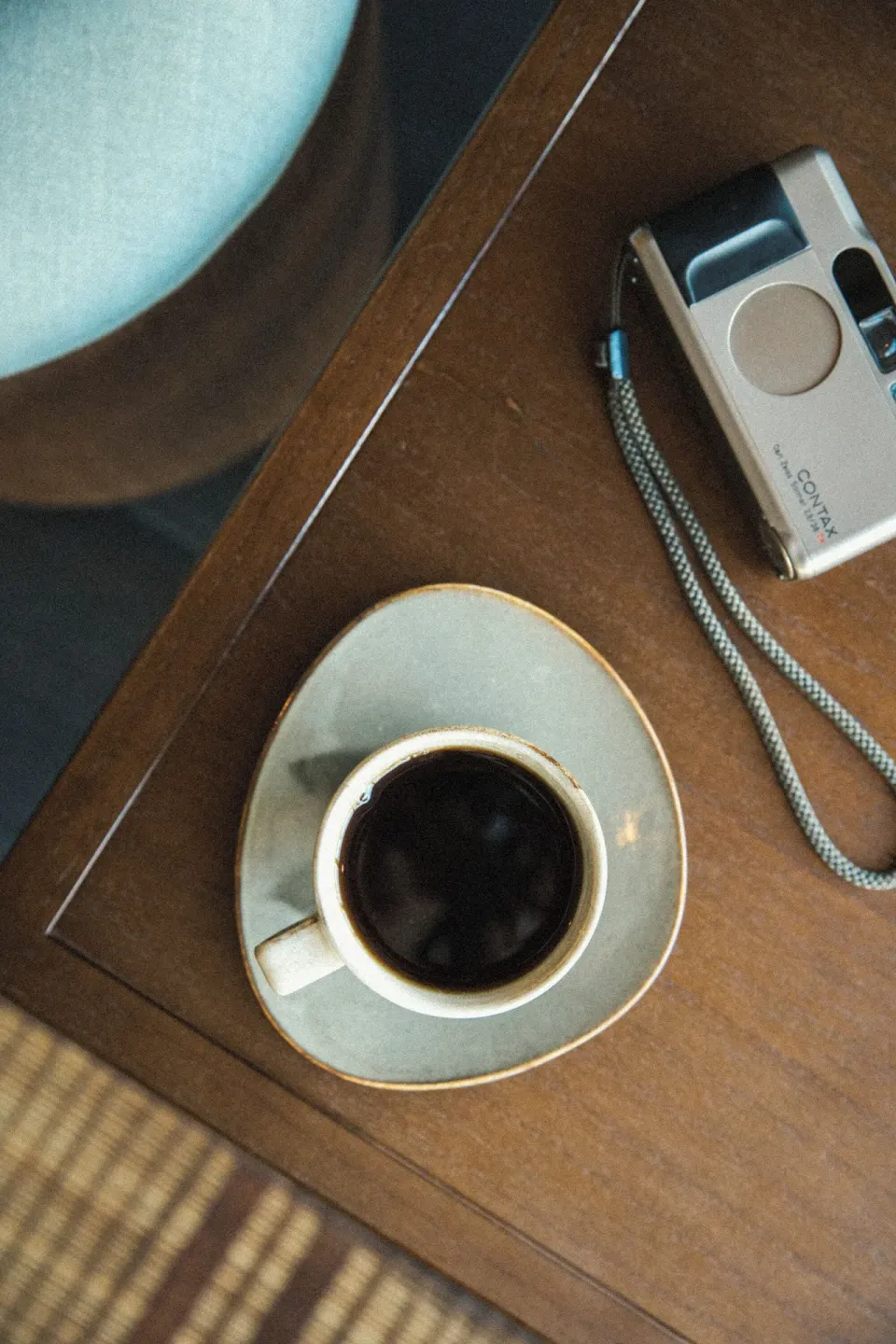 Coffee cup and compact camera on a wooden table at Romer House Waikiki.