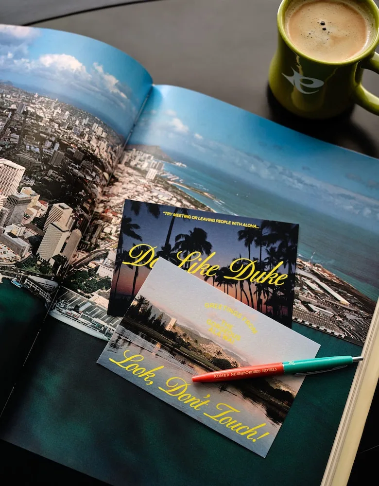 Coffee, postcards and a Waikiki photo book on a table at Romer House Waikiki.