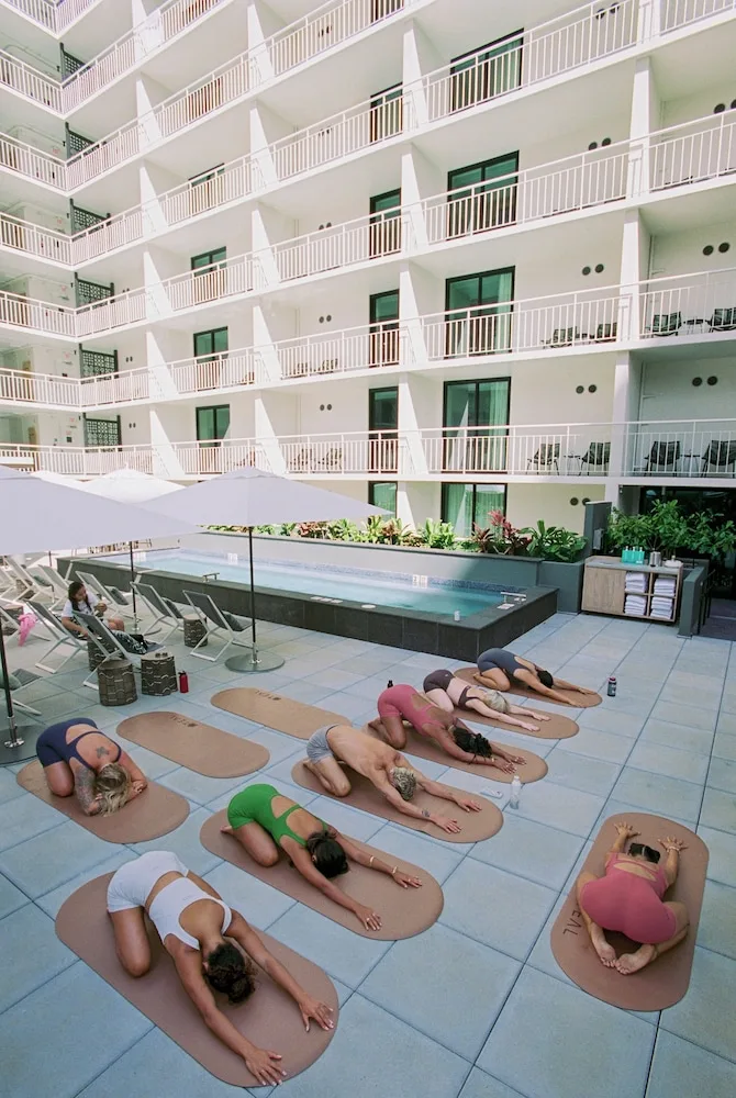 Courtyard pool deck yoga class beside lounge chairs at Romer House Waikiki.