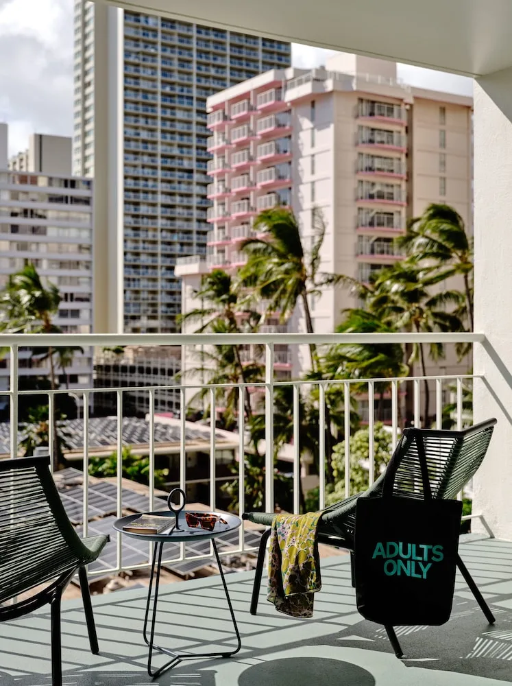 Balcony seating with city buildings and palm trees at Romer House Waikiki.