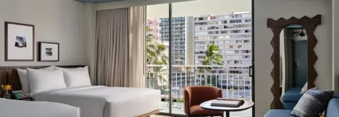Guest room with bed, seating and balcony city view at Romer House Waikiki.