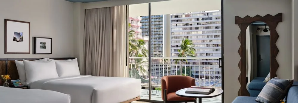 Guest room with bed, seating and balcony city view at Romer House Waikiki.