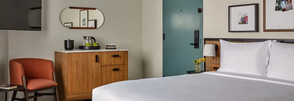 King bed, lounge chair, and wood cabinet in a guest room at Romer House Waikiki.