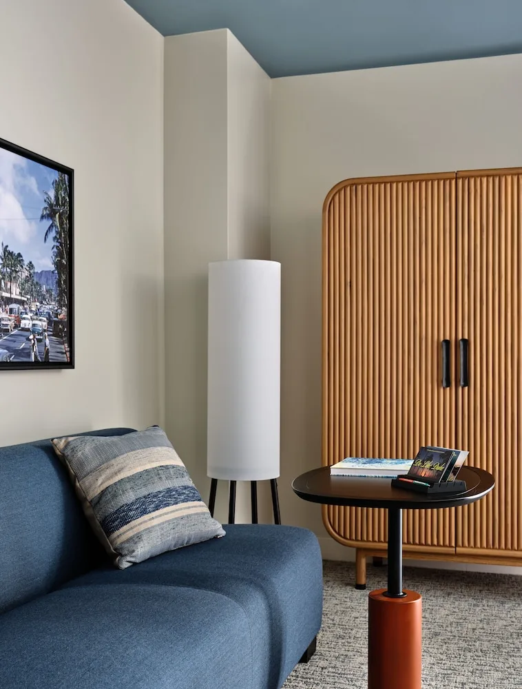 Blue sofa, round table, floor lamp and ribbed cabinet in a guest room at Romer House Waikiki.