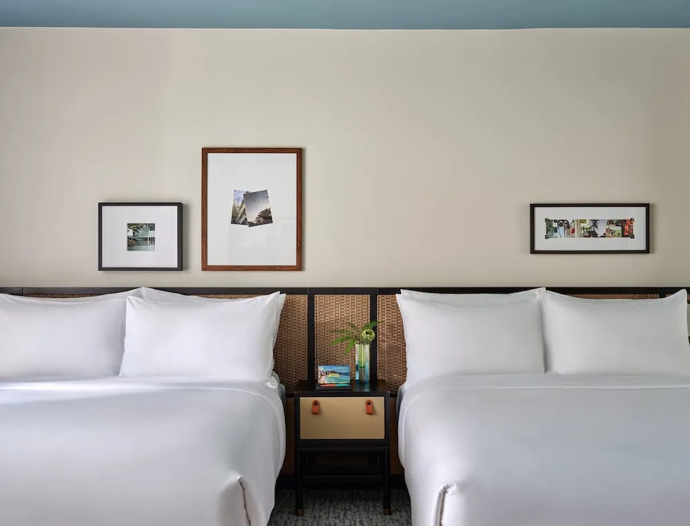 Two white beds with framed art above the headboards at Romer House Waikiki.