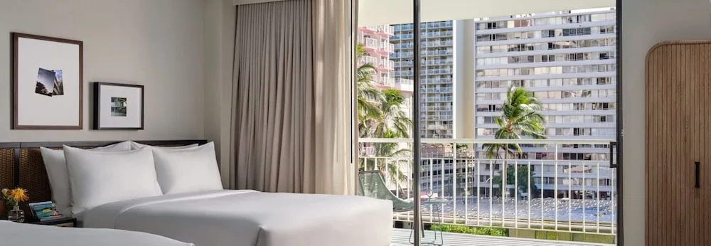Guest room with two beds and a balcony view at Romer House Waikiki.