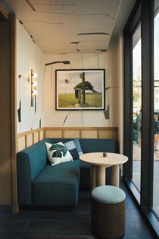 Lobby window nook with teal banquette seating and round table at Romer House Waikiki.