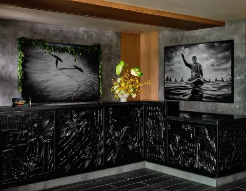 Reception desk with carved black panels and surf photography at Romer House Waikiki.