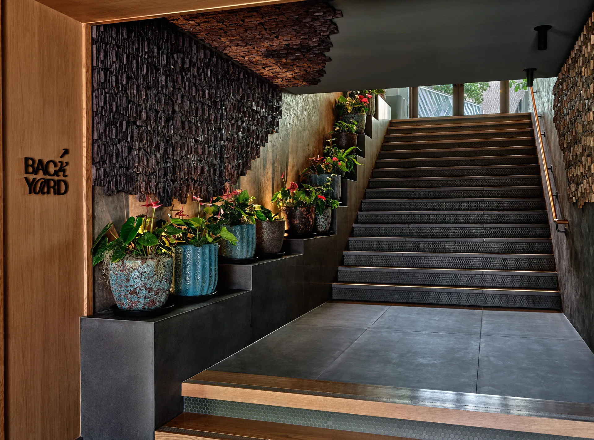 Stairway entrance with Backyard sign and potted plants at Romer House Waikiki.