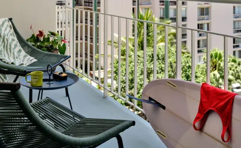 Balcony seating with lounge chairs and a bodyboard at Romer House Waikiki.