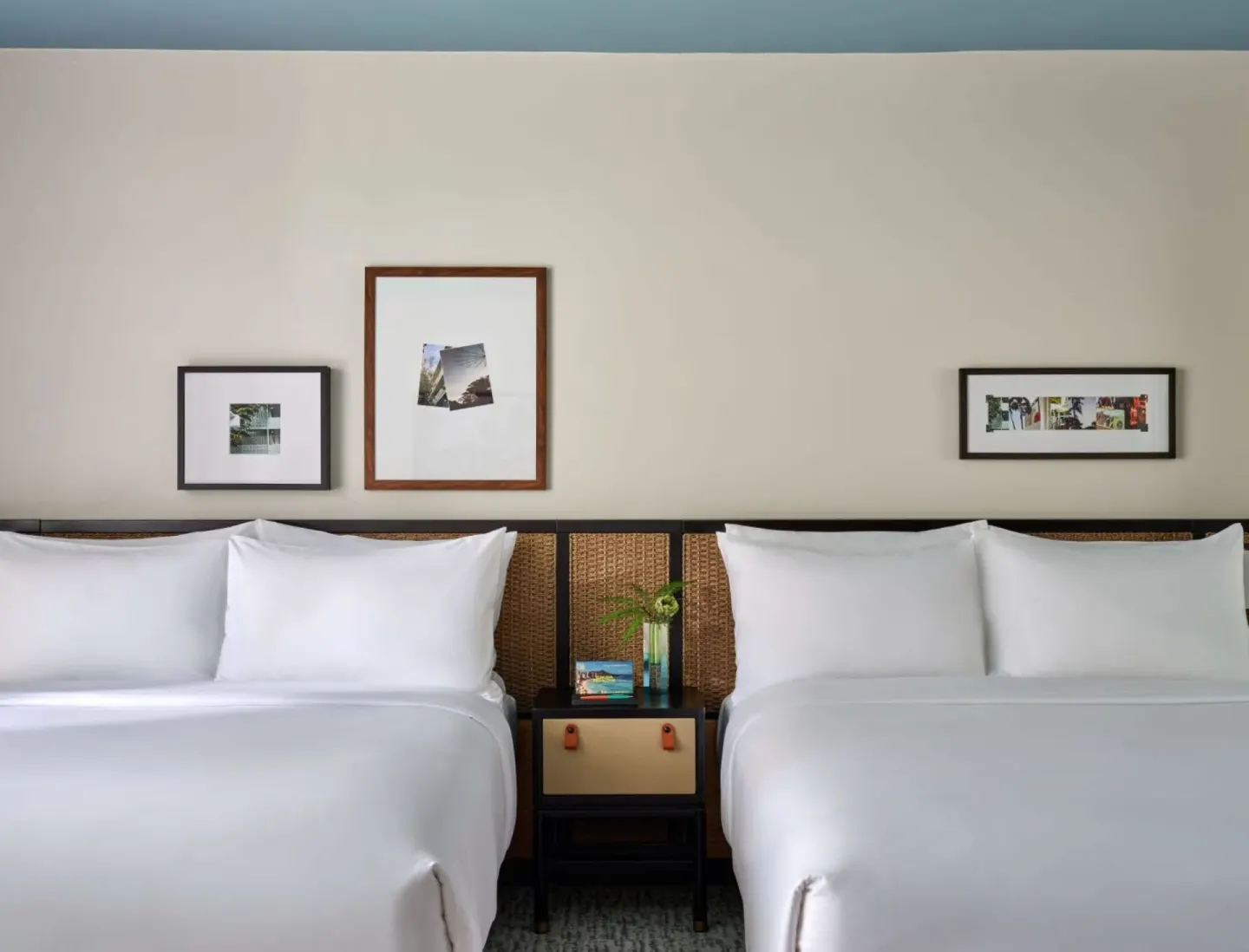 Two beds with white linens in a Deluxe Room at Romer House Waikiki.