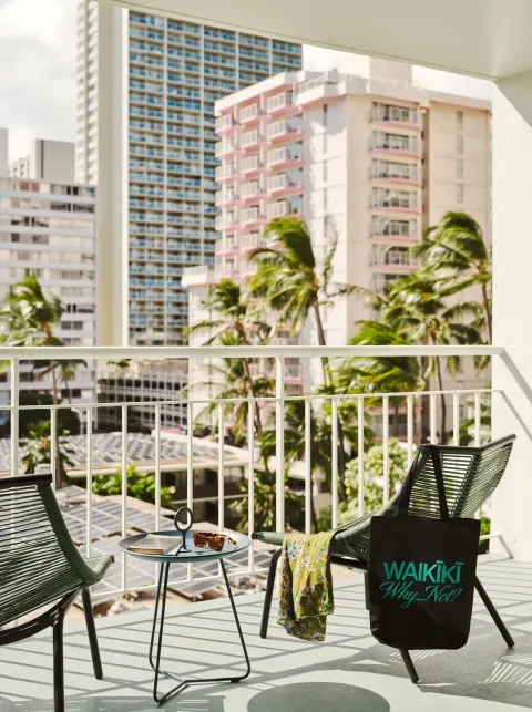 Deluxe Room balcony seating with palm and city views at Romer House Waikiki.