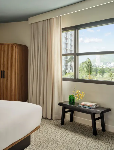 Deluxe Room window area with wardrobe, bench, and city view at Romer House Waikiki.