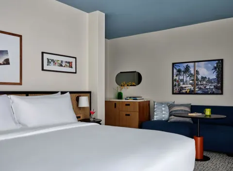 King bed, blue daybed, dresser and wall art in a Premium Room Balcony at Romer House Waikiki.