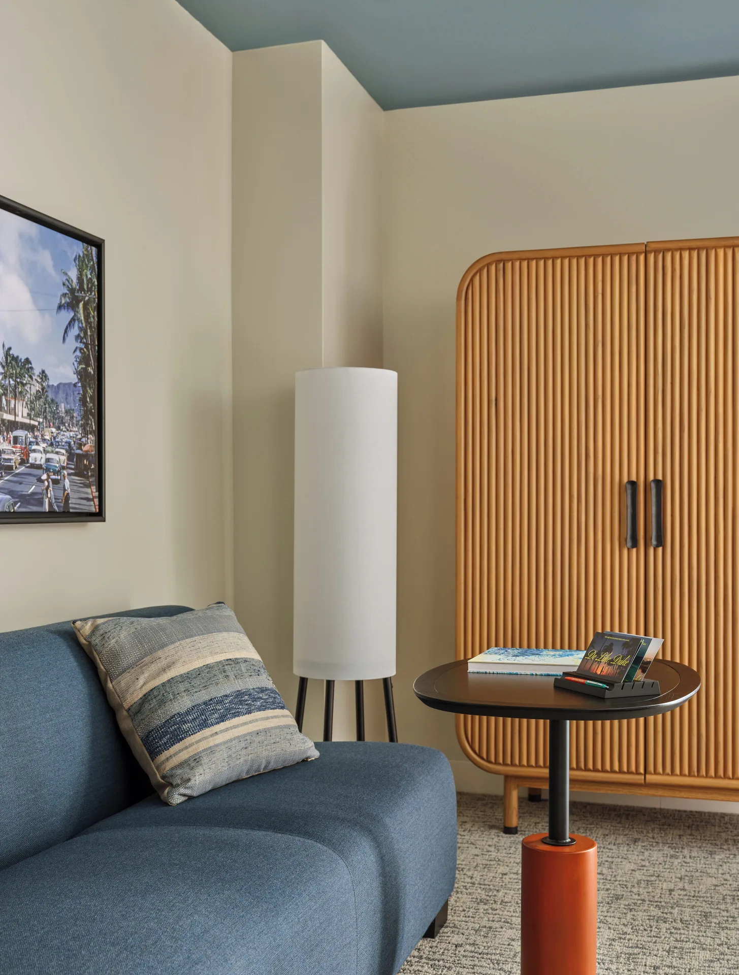 Blue sofa, round table, lamp and wood wardrobe in a Premium Room Balcony at Romer House Waikiki.