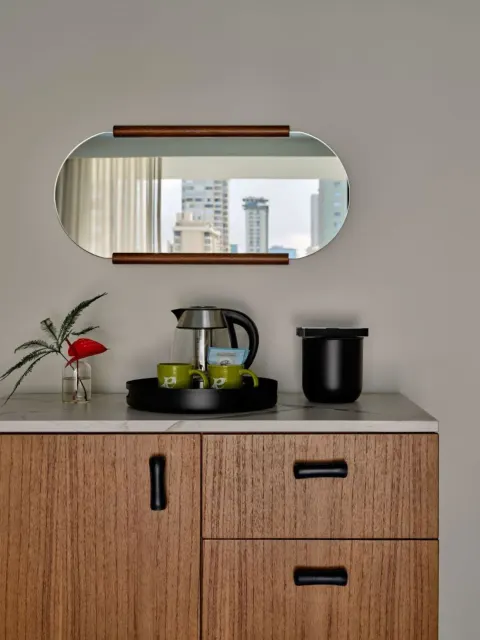 Standard Room refreshment cabinet with mirror, kettle, mugs, and flower at Romer House Waikiki.
