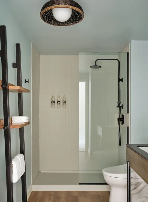 Two Bedrooms Suite bathroom with glass shower, black fixtures, towels, and vanity at Romer House Waikiki.