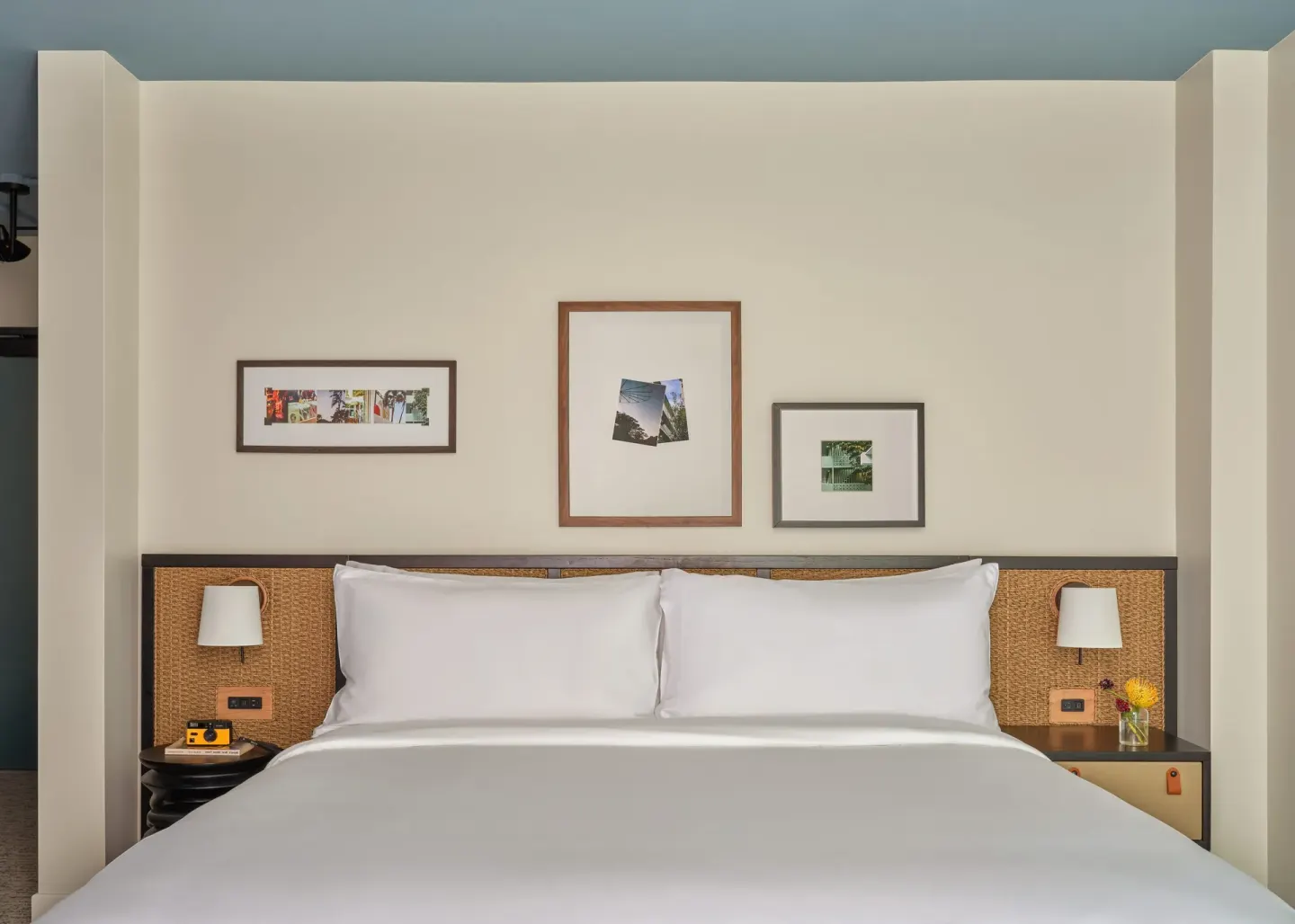 White king bed with woven headboard and framed art in a Two Bedrooms Suite at Romer House Waikiki.