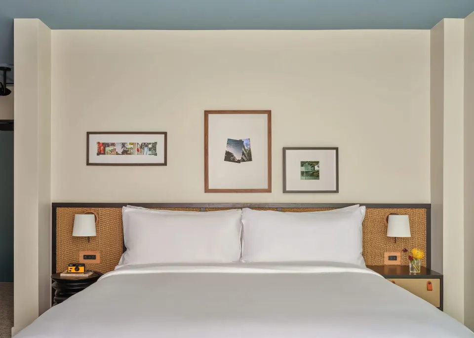 White king bed with woven headboard and framed art in a Two Bedrooms Suite at Romer House Waikiki.