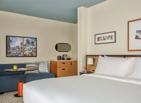 Bed, sofa, table, cabinet, and wall art in a Two Bedrooms Suite at Romer House Waikiki.