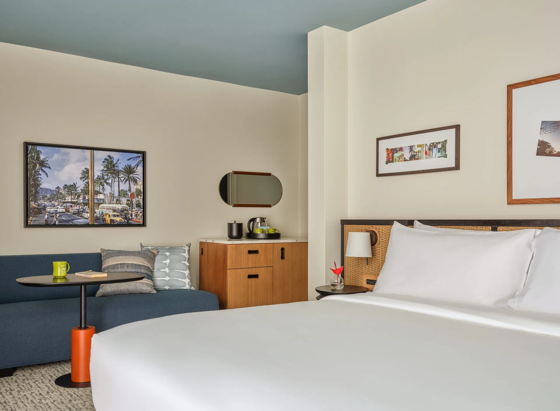 Bed, sofa, table, cabinet, and wall art in a Two Bedrooms Suite at Romer House Waikiki.
