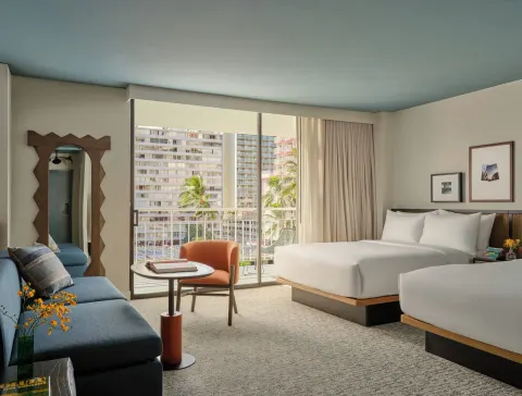 Two beds, sofa, chair, and balcony windows in a Two Bedrooms Suite at Romer House Waikiki.