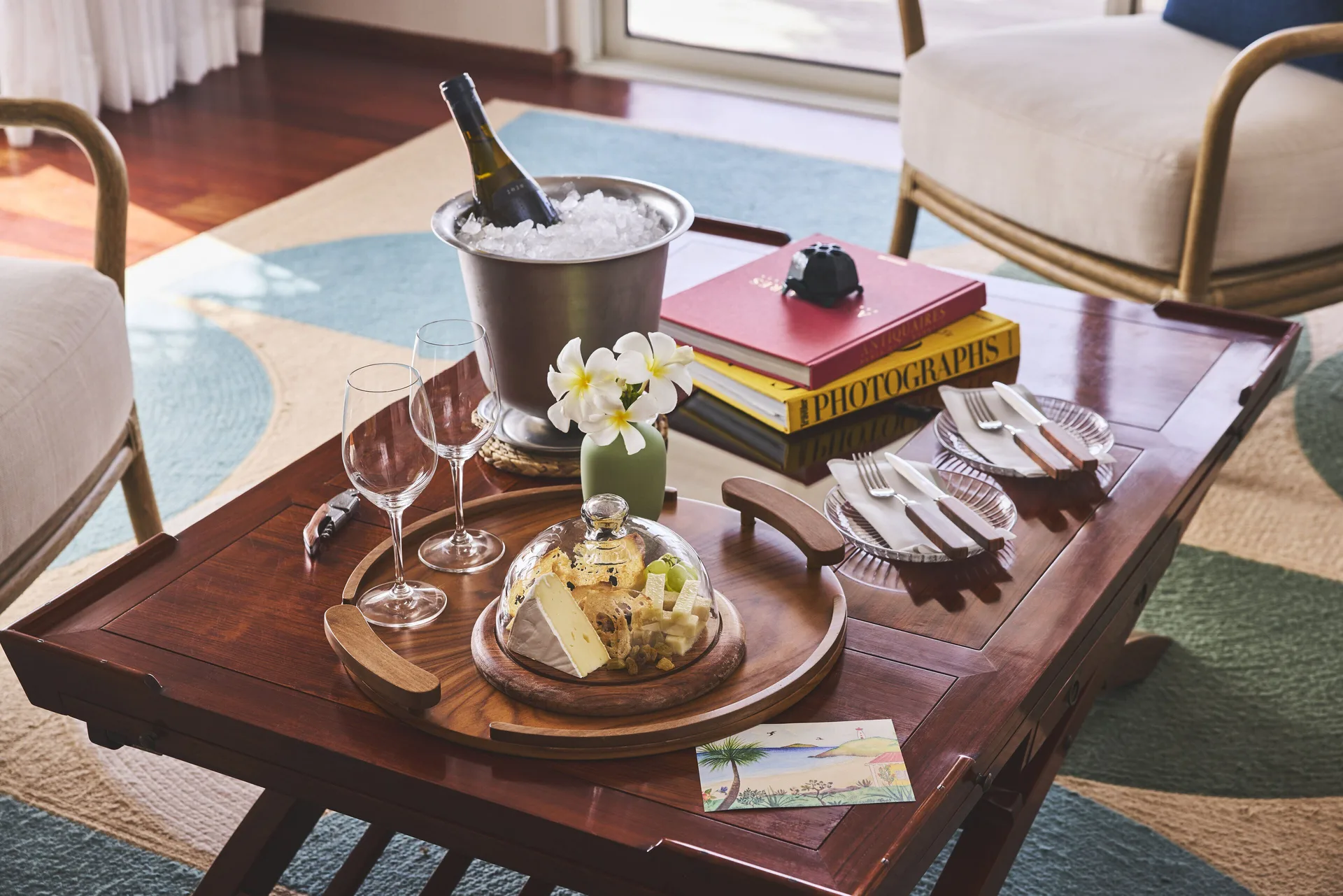 Coffee table with chilled bottle, glasses, flowers, and snacks at Rosewood Le Guanahani St Barth.