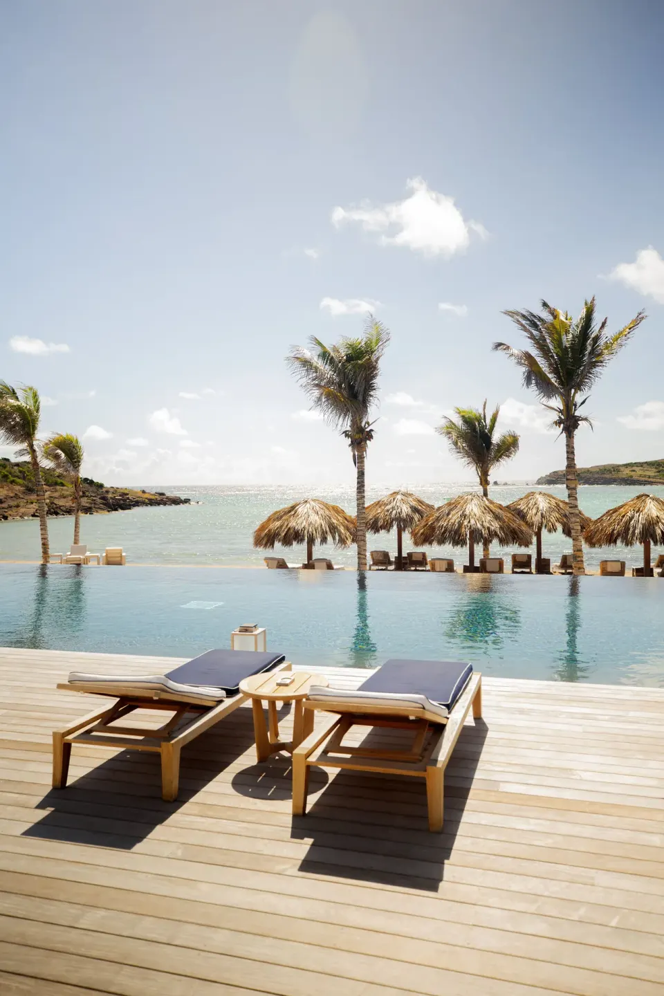 Infinity pool with loungers, palms and sea beyond at Rosewood Le Guanahani St Barth.