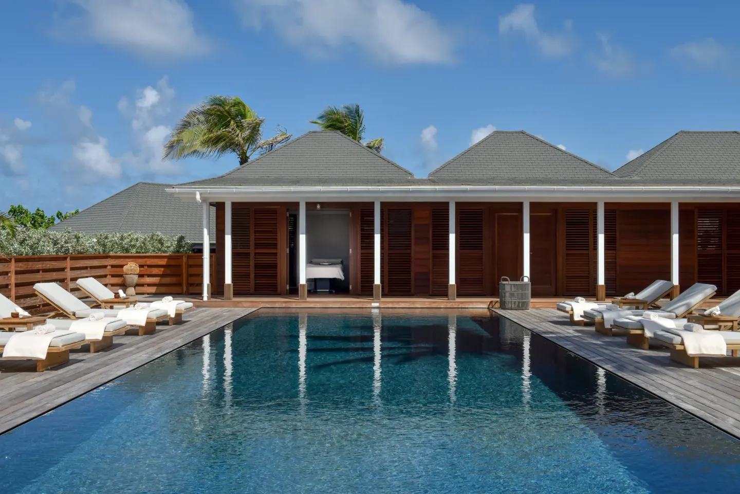 Long pool with lounge chairs and shuttered buildings at Rosewood Le Guanahani St Barth.