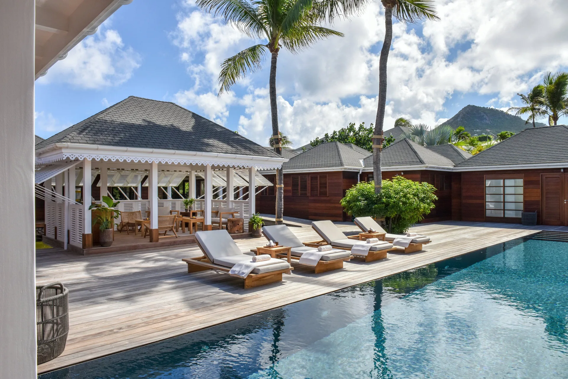 Pool deck with loungers, palms, and pavilion at Rosewood Le Guanahani St Barth.