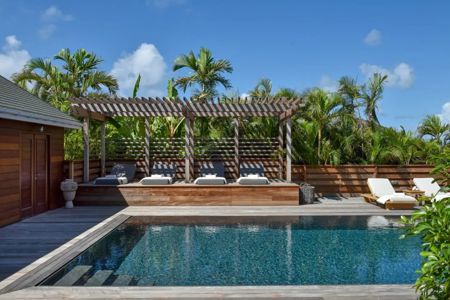 Poolside pergola and loungers among palms at Rosewood Le Guanahani St Barth.