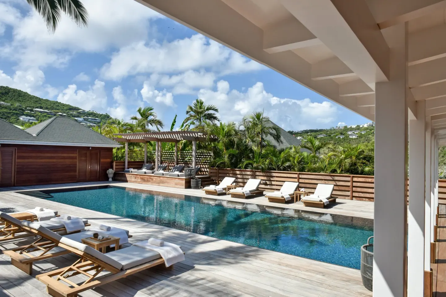 Shaded terrace overlooking a pool and palm landscaping at Rosewood Le Guanahani St Barth.