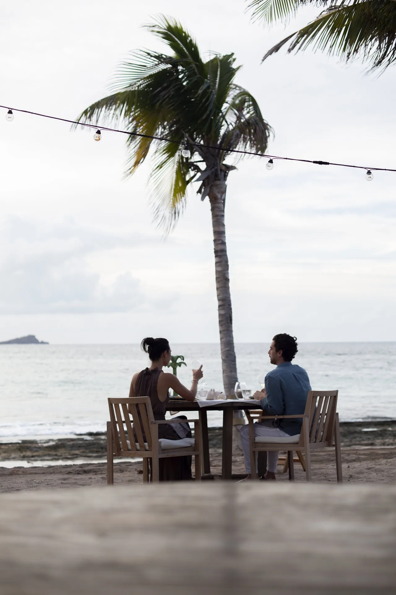 Couple dining by the beach under a palm at Rosewood Le Guanahani St Barth.