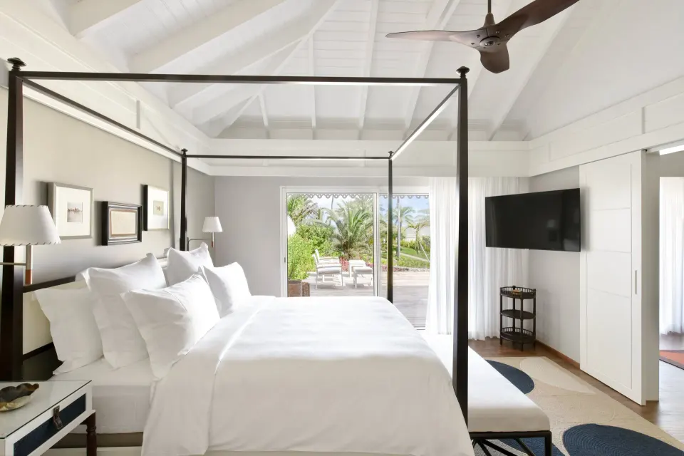 Garden Suite bedroom with four-poster bed and patio view at Rosewood Le Guanahani St Barth.
