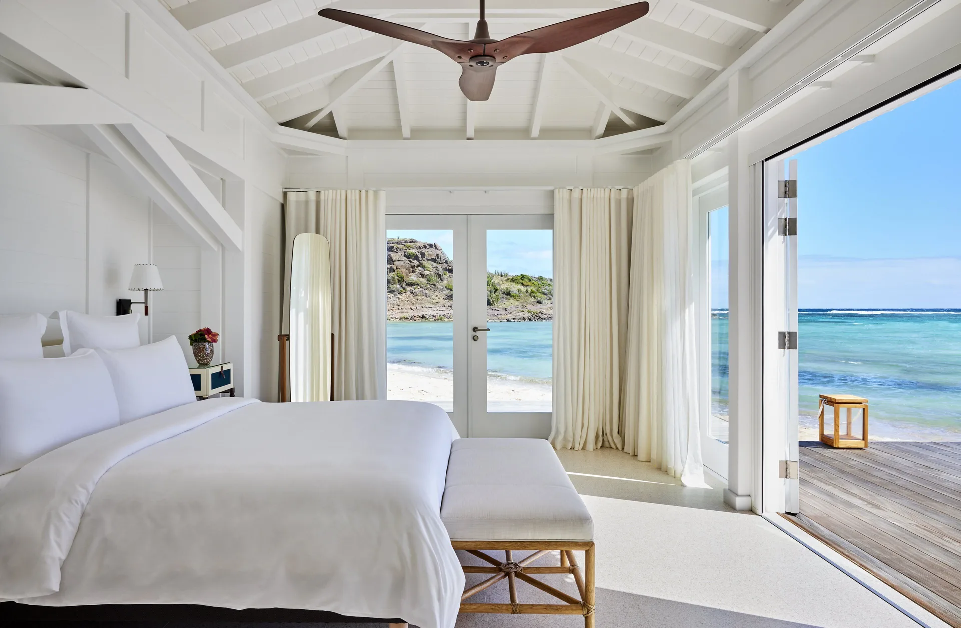 Lagoon Suite king bed opens to lagoon and deck views at Rosewood Le Guanahani St Barth.