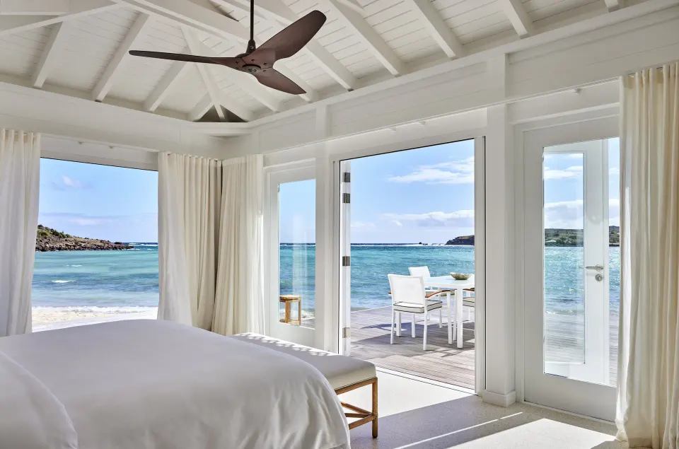 Lagoon Suite king bed and terrace facing the water at Rosewood Le Guanahani St Barth.