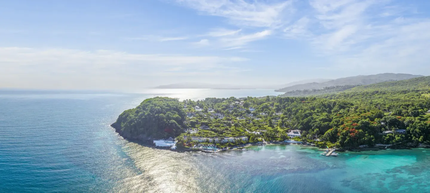 An aerial view shows the resort peninsula and bright bay at Round Hill Hotel And Villas.