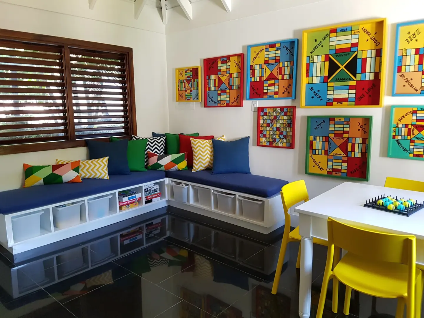 Children's game room with benches, board games and bright chairs at Round Hill Hotel And Villas.
