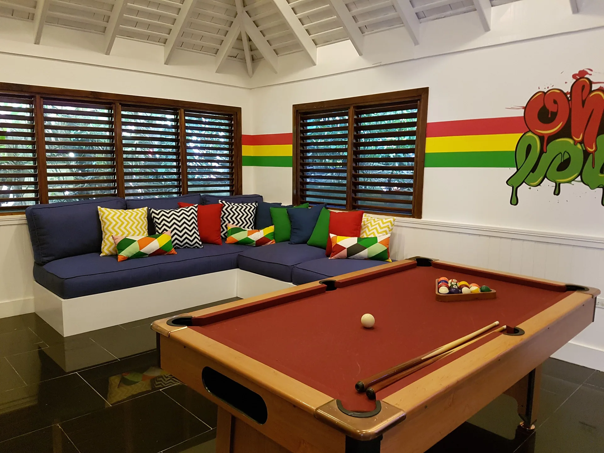 Colorful game room with pool table and lounge seating at Round Hill Hotel And Villas.