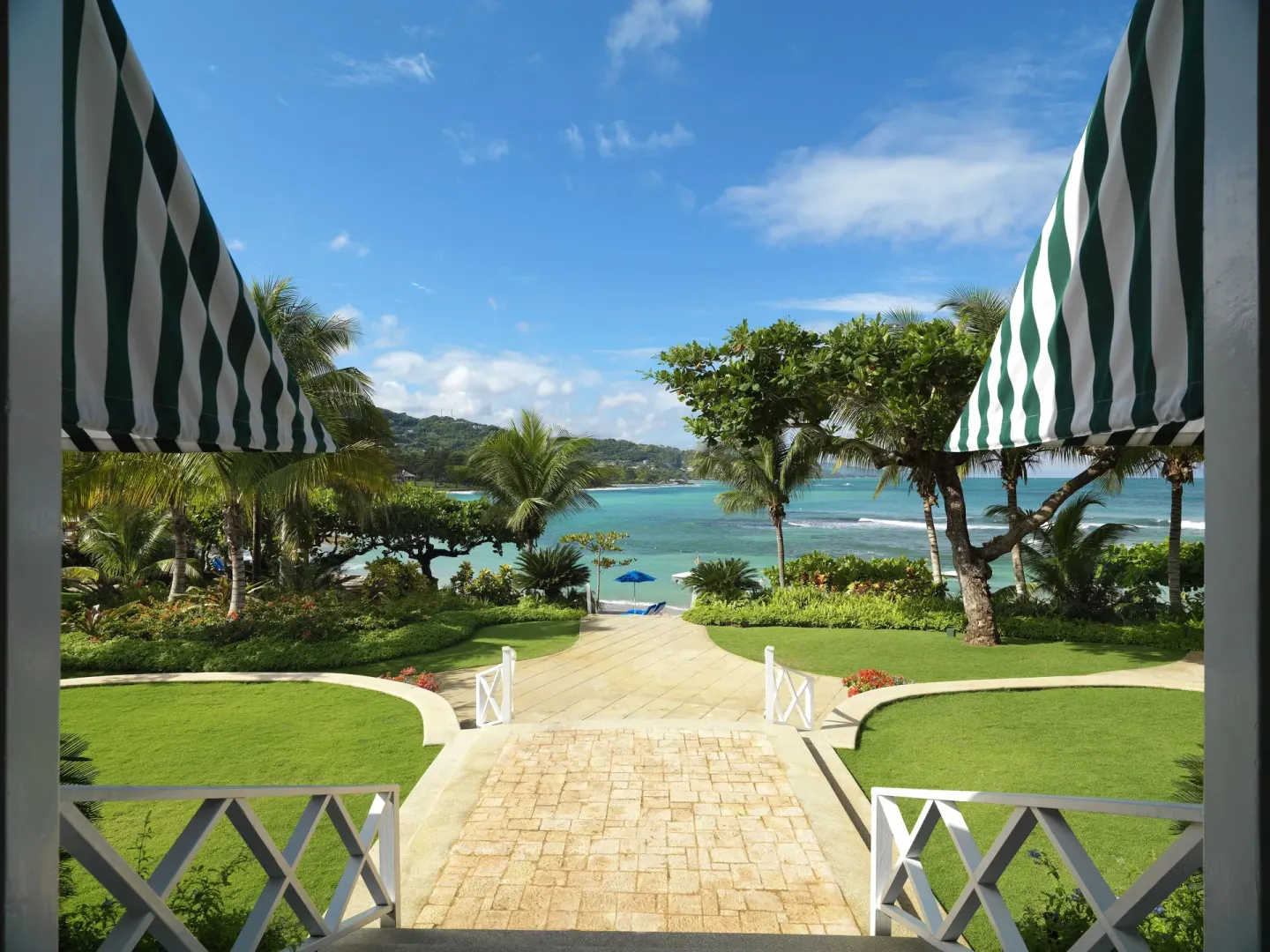 Garden path leading from striped awnings to the beach at Round Hill Hotel And Villas.