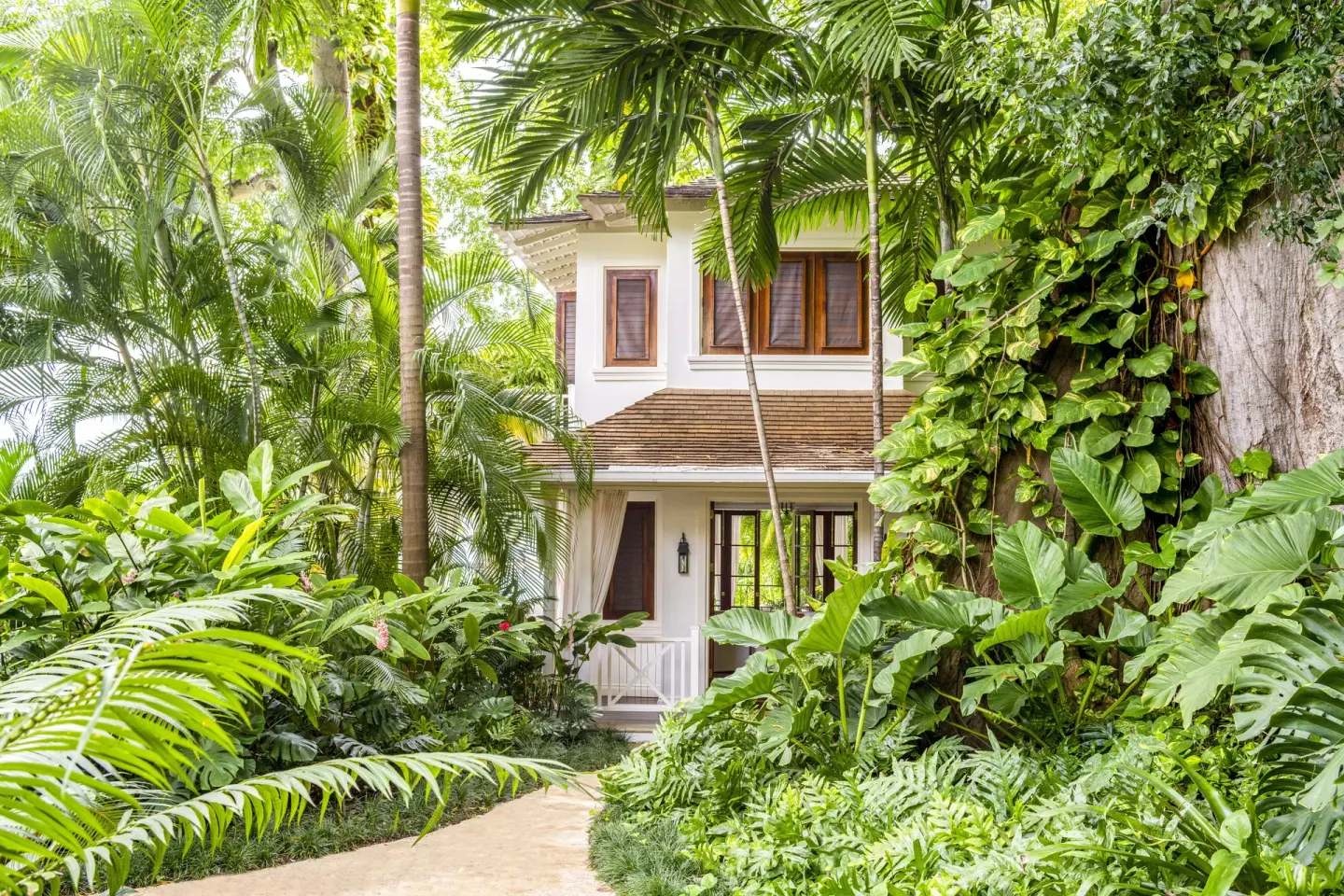 Garden path leading to a white villa at Round Hill Hotel And Villas.