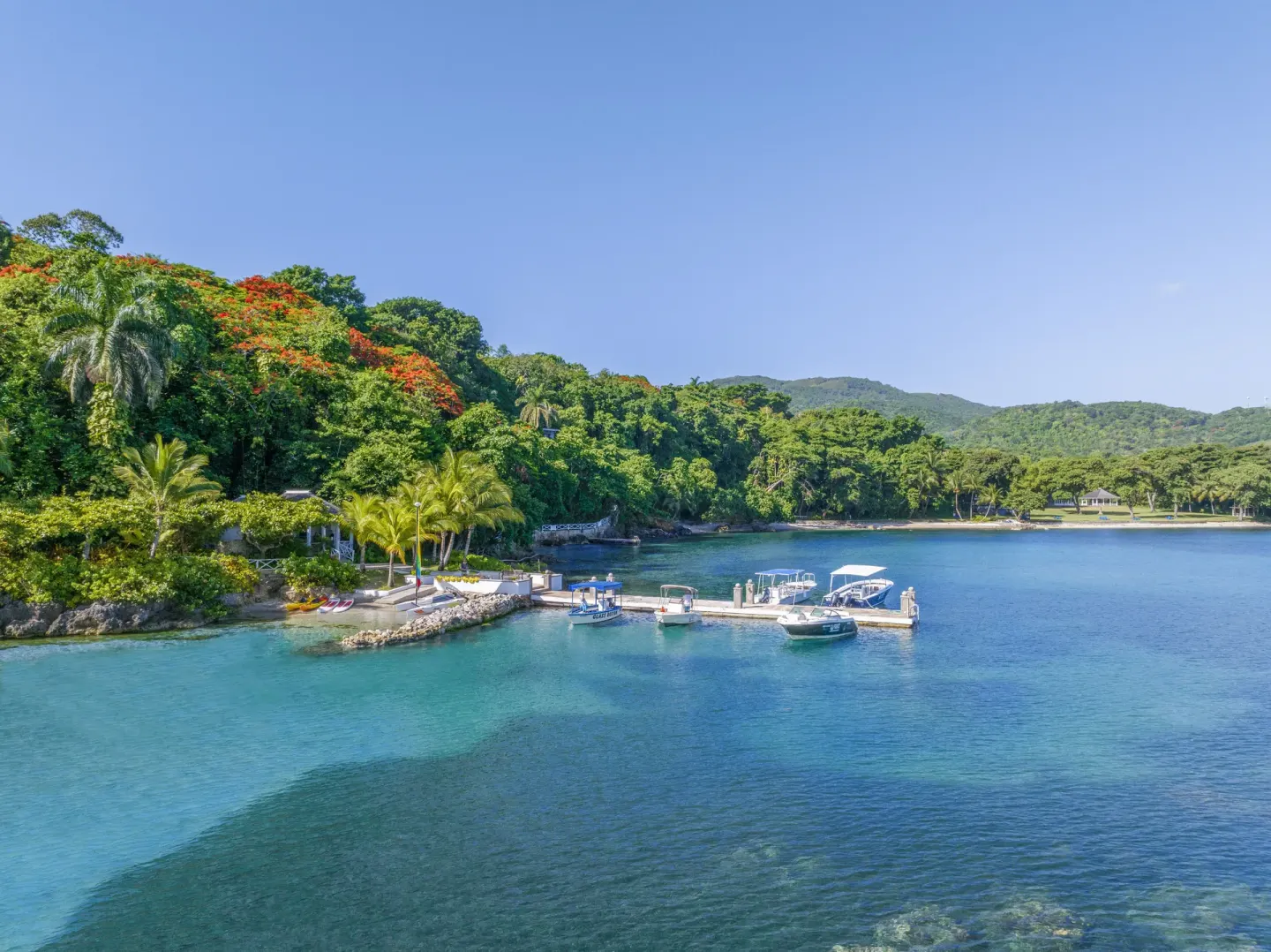 A small marina and turquoise bay sit below green hills at Round Hill Hotel And Villas.