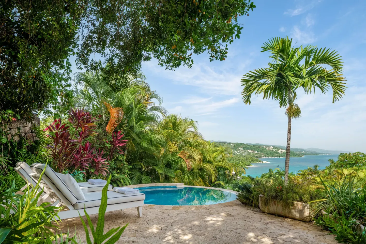 Pool terrace with loungers and ocean view at Round Hill Hotel And Villas.