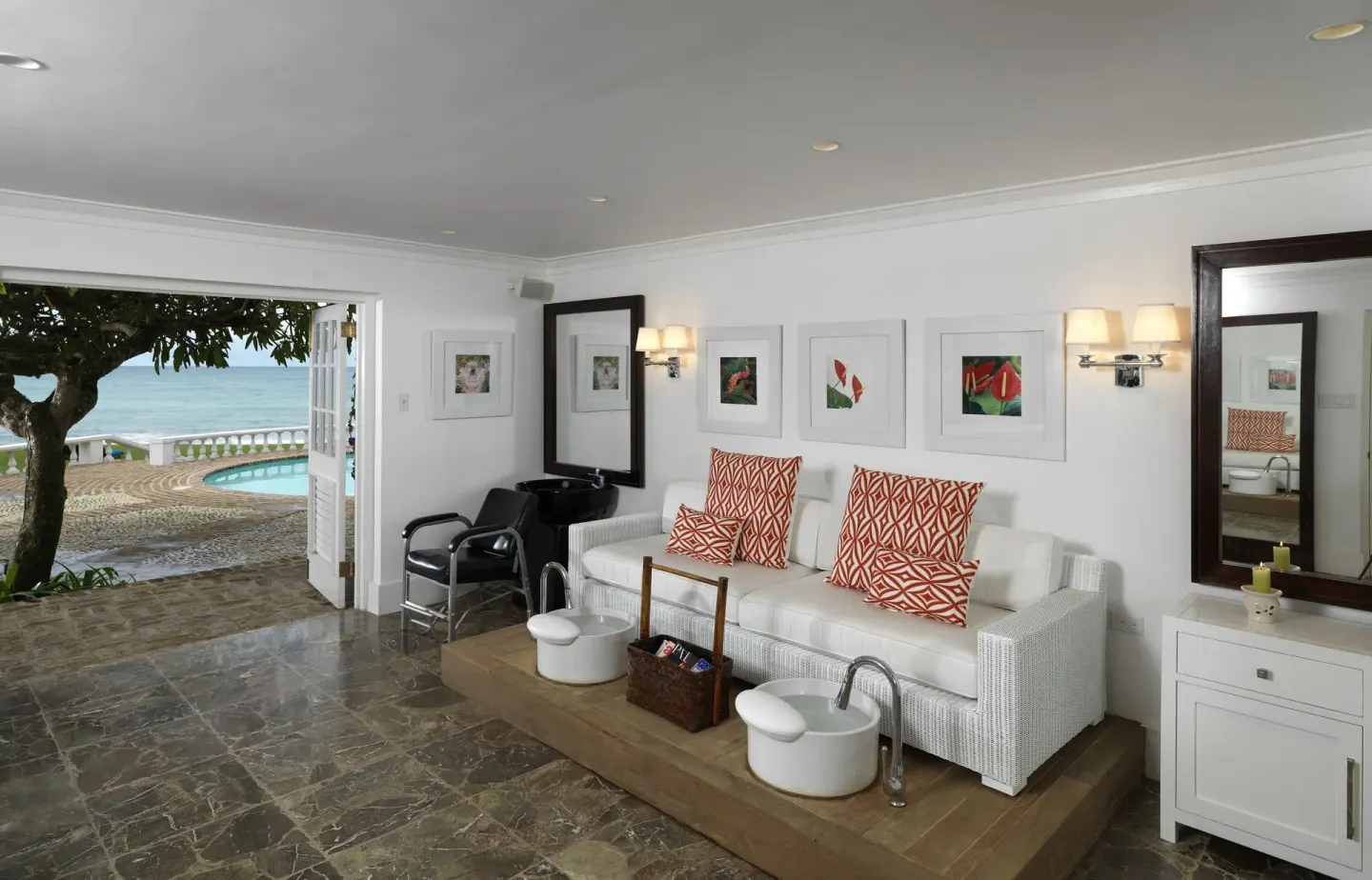 Spa lounge with white sofa, pedicure chairs, and ocean view at Round Hill Hotel And Villas.