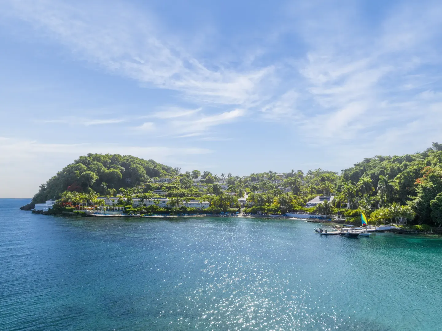 Sunlit water, docks, and hillside greenery fill the bay at Round Hill Hotel And Villas.