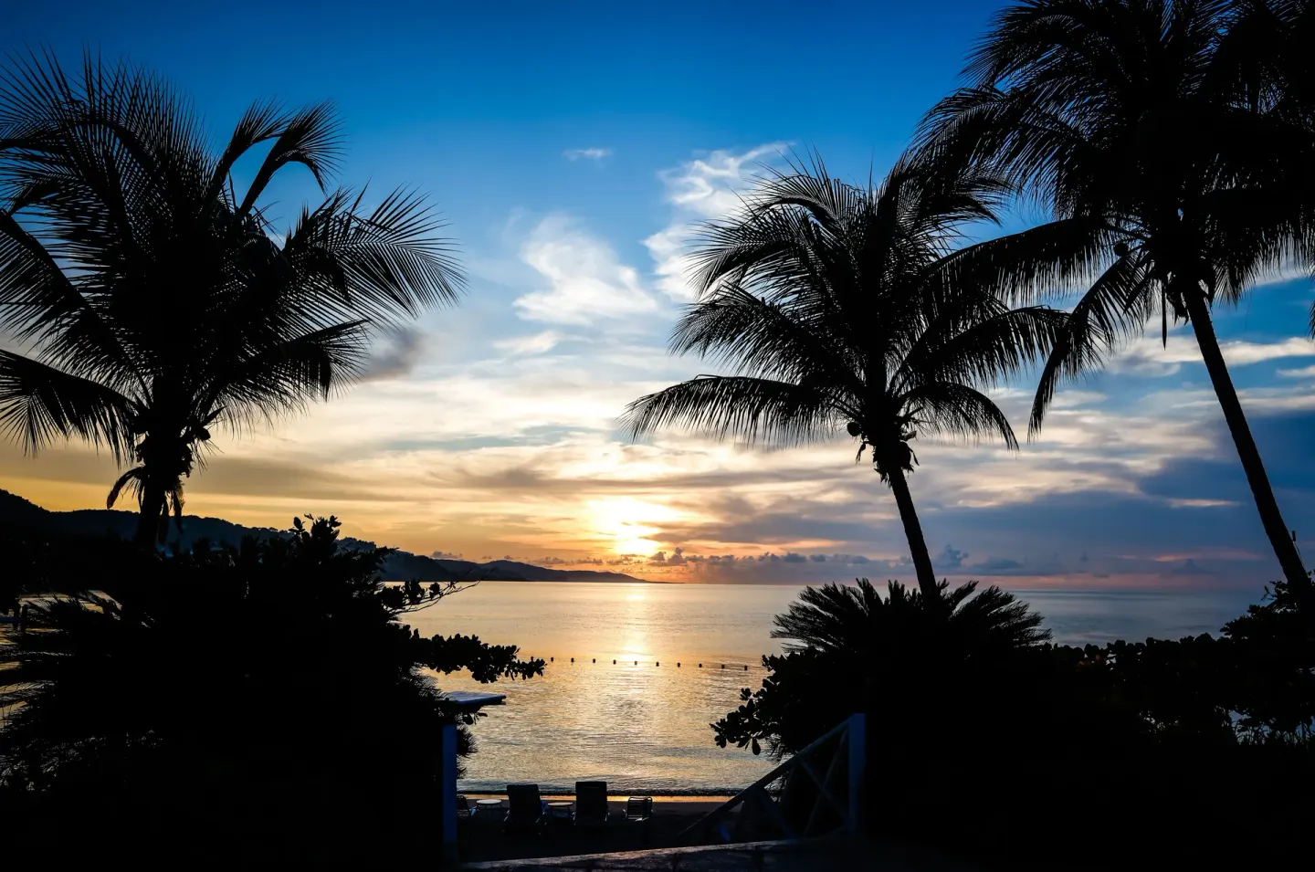 Palm silhouettes frame a sunset over the bay at Round Hill Hotel And Villas.
