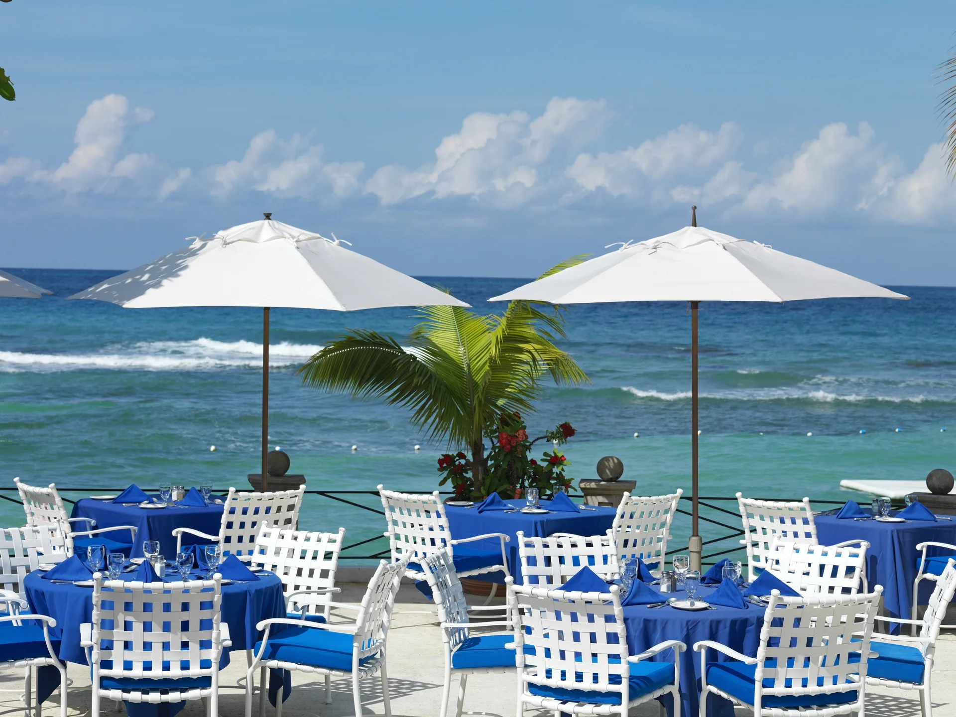 Seaside terrace dining with blue table linens at Round Hill Hotel And Villas.