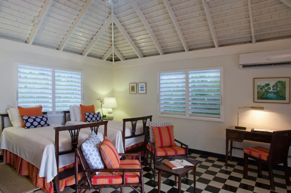 Twin bedroom with sitting chairs in a Classic Villa at Round Hill Hotel And Villas.